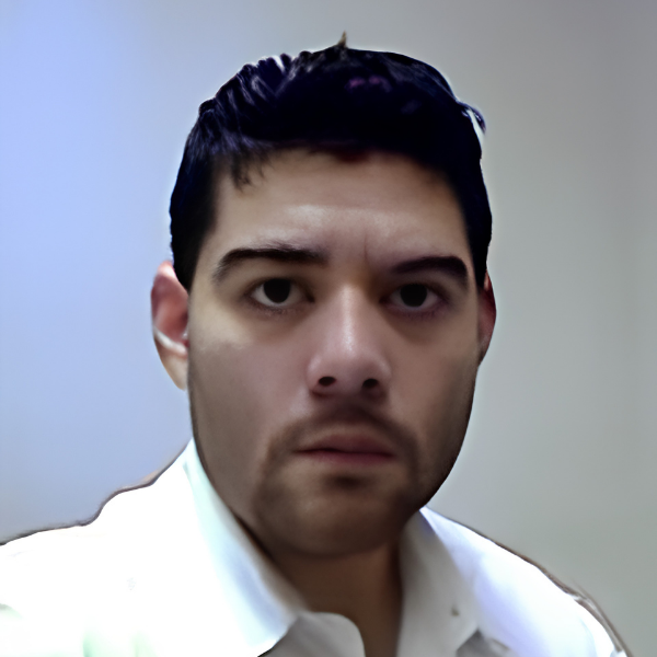 Photo of Anthony Hernandez, a man with short dark hair and stubble wears a white shirt, looking directly at the camera with a neutral expression on a plain background.