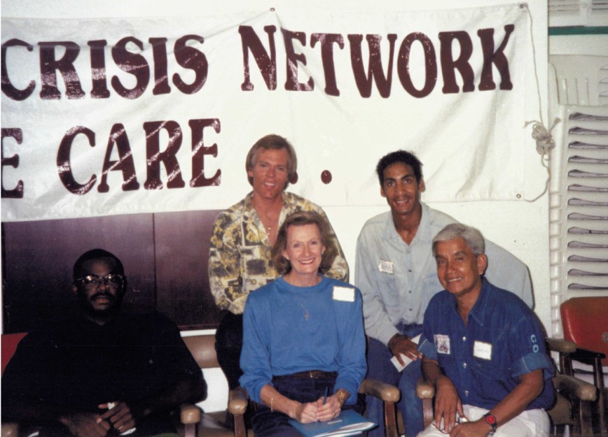 Five people are seated in front of a Health Crisis Network banner. They appear content, suggesting a supportive community atmosphere.