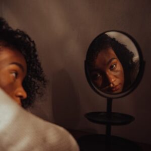 Young woman watching her reflection in mirror