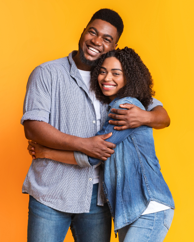 Two people hugging in front of a yellow background, symbolizing support and HIV stigma reduction.