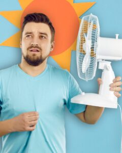 A man with dark hair and facial wearing a blue-colored t-shirt holding a fan