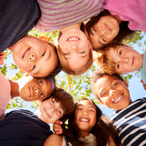 overheating in the summer heat group of children standing in a circle outdoors under bright sun and green trees