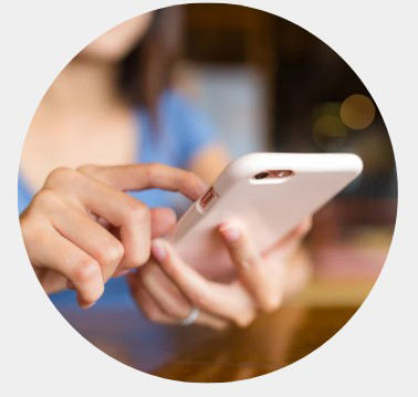 Close-up of hands tapping a white smartphone, with a softly blurred café background creating a warm, focused, modern technology mood.