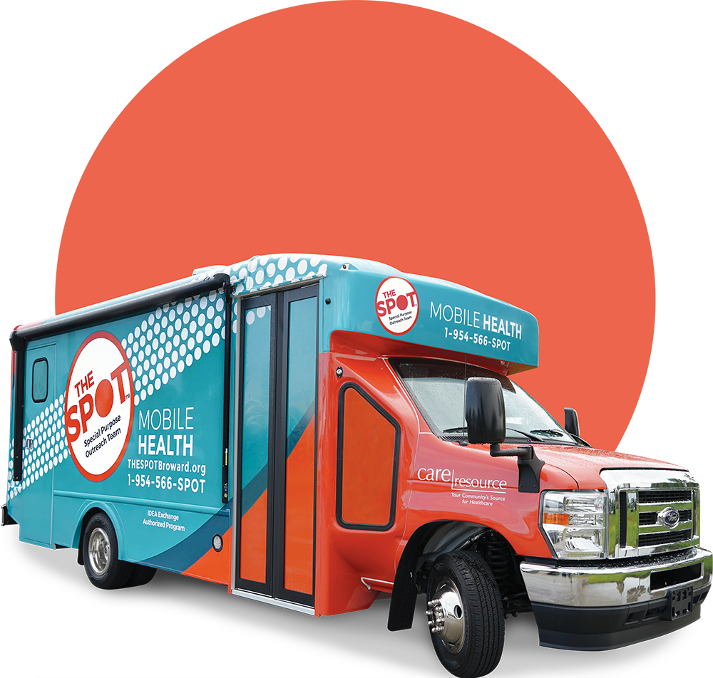 Colorful mobile health clinic van with The Spot branding against a large red circle backdrop. Vibrant and inviting community outreach vehicle.