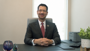 Dr. Steven Santiago seated at a desk at Care Resource, discussing HIV treatment research and patient care.